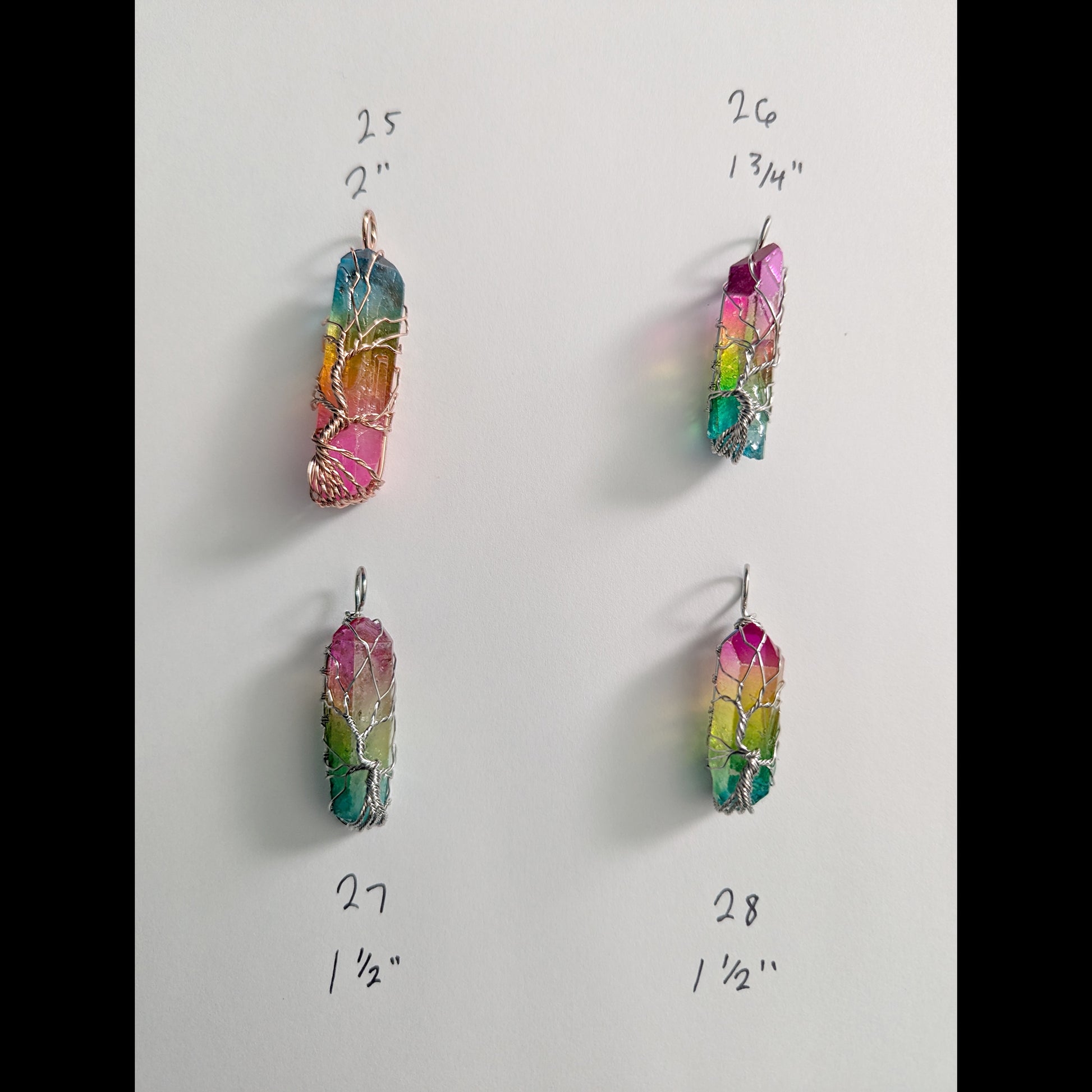 Natural Rainbow quartz crystal tree of life wire wrapped pendants arranged in rows on a white background