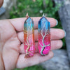 Natural Rainbow quartz crystal tree of life wire wrapped pendants in hand outdoors