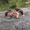 Copper horse head bracelet on a wooden surface with a natural background