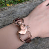 Copper bracelet with a horse design on a wrist against a wooden background