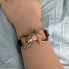 Copper horse head and bit bracelet on a wrist against a light fabric background