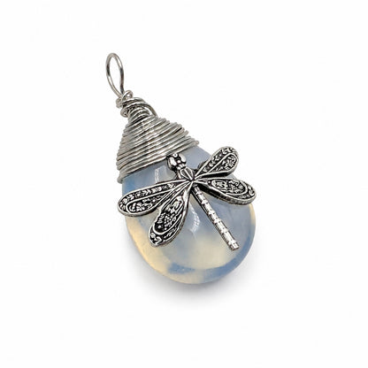 A silver dragonfly pendant necklace resting on a plain white background. The pendant features a blue synthetic opal stone  with a detailed dragonfly.