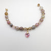 Beaded bracelet with pink heart charm on a white background