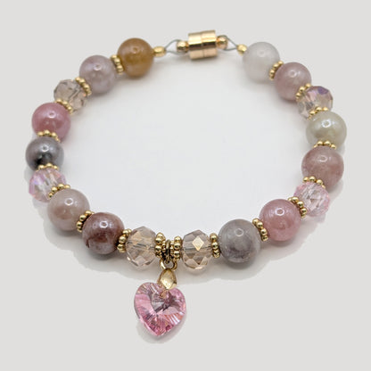 Beaded bracelet with pink heart charm on a light gray background