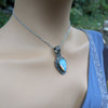 Necklace with a blue pendant on a mannequin against a blurred green background