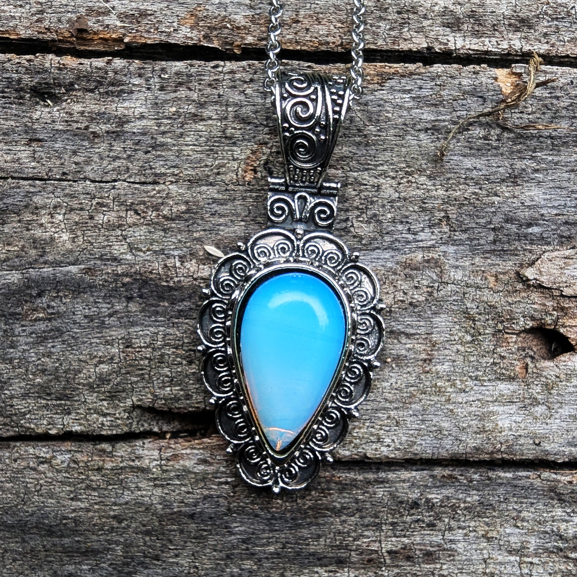 Silver pendant with a blue stone on a wooden surface