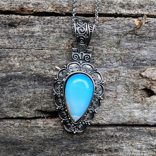 Silver pendant with a blue stone on a wooden surface