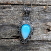 Silver pendant with a blue stone on a wooden surface