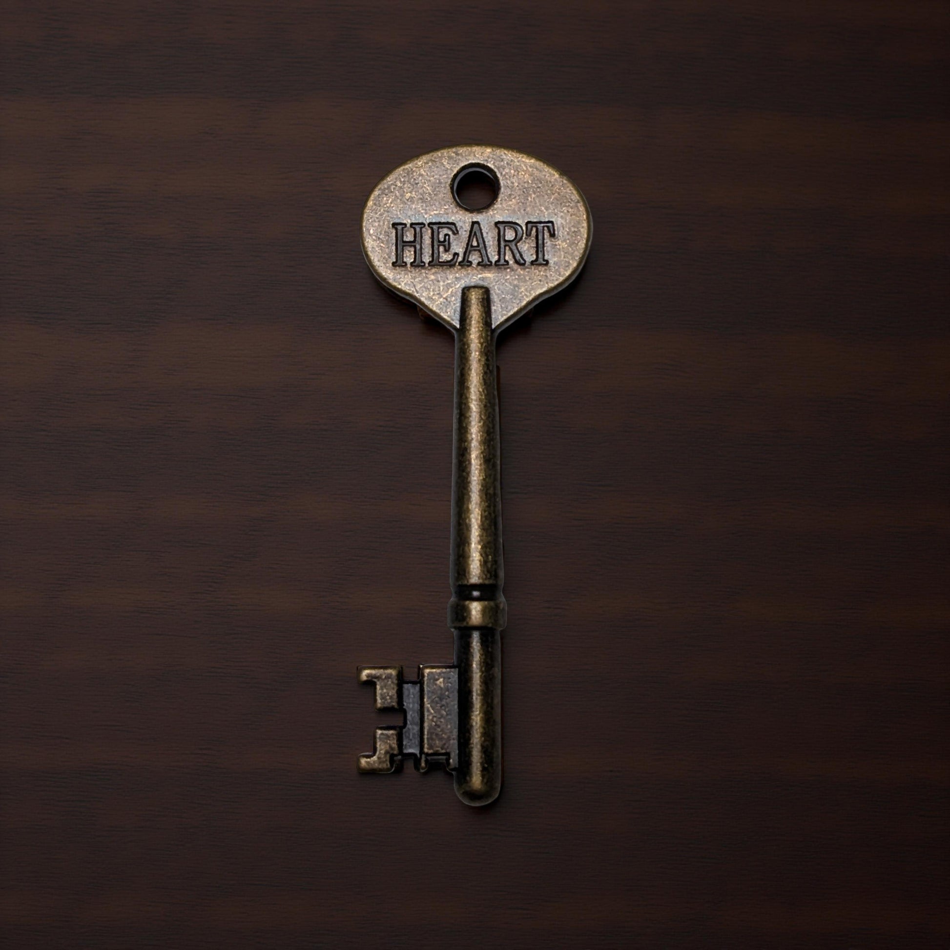 Vintage key with 'HEART' engraved on a dark brown background