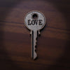 Decorative key-shaped object with 'LOVE' engraved on a wooden surface