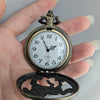 Vintage pocket watch held in a hand with a plain background