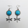 Pair of earrings with turquoise stones and dragonfly designs on a white background