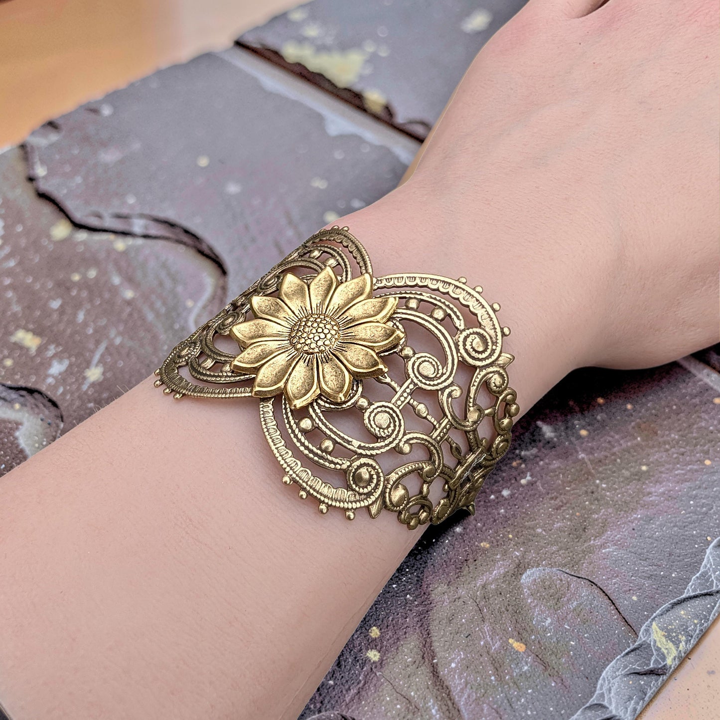 Vintage style brass floral sunflower statement bracelet on a wrist