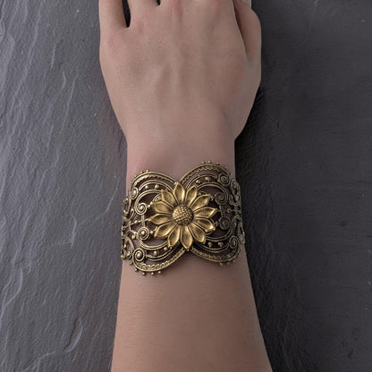 Vintage style brass floral sunflower statement bracelet on a wrist against a dark background