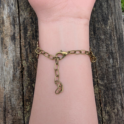 Gold chain bracelet with a unique clasp on a wrist against a wooden background