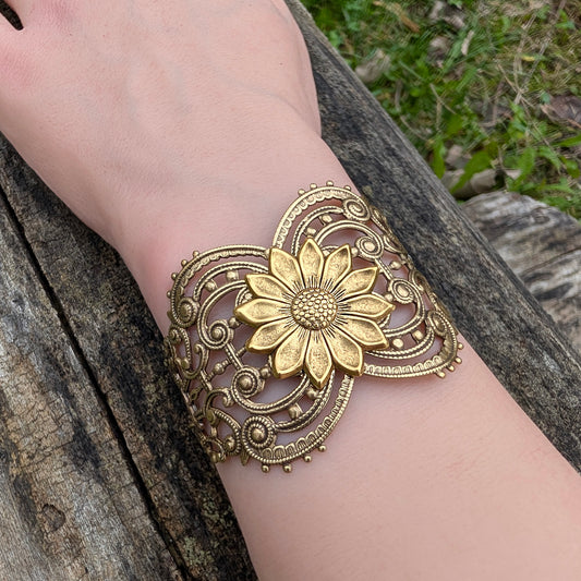 Gold floral sunflower bracelet on a wrist with a natural background