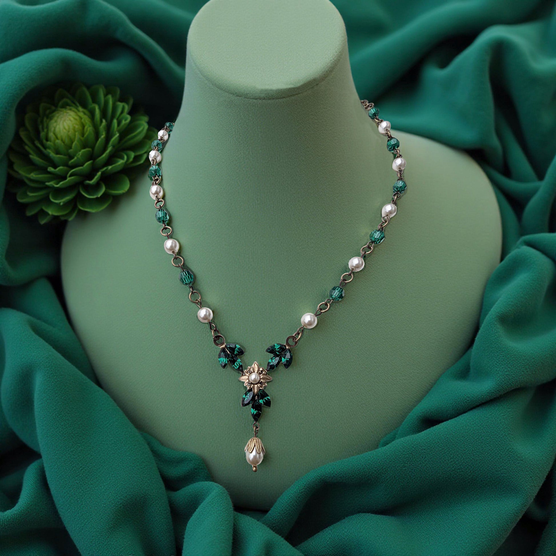 Vintage Art Deco Swarovski Emerald crystal and pearl floral necklace on a green mannequin bust with green fabric background
