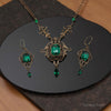 Jewelry set with necklace and earrings featuring green gemstones on a dark surface.