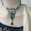 Model wearing brass cherub necklace and earrings set with emerald Swarovski crystals in romantic vintage style