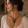 Vintage brass emerald cherub necklace and earring set worn by a woman.