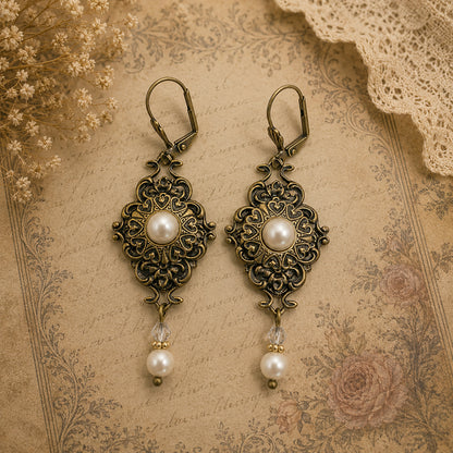 Pair of ornate earrings with pearls on an antique-style background