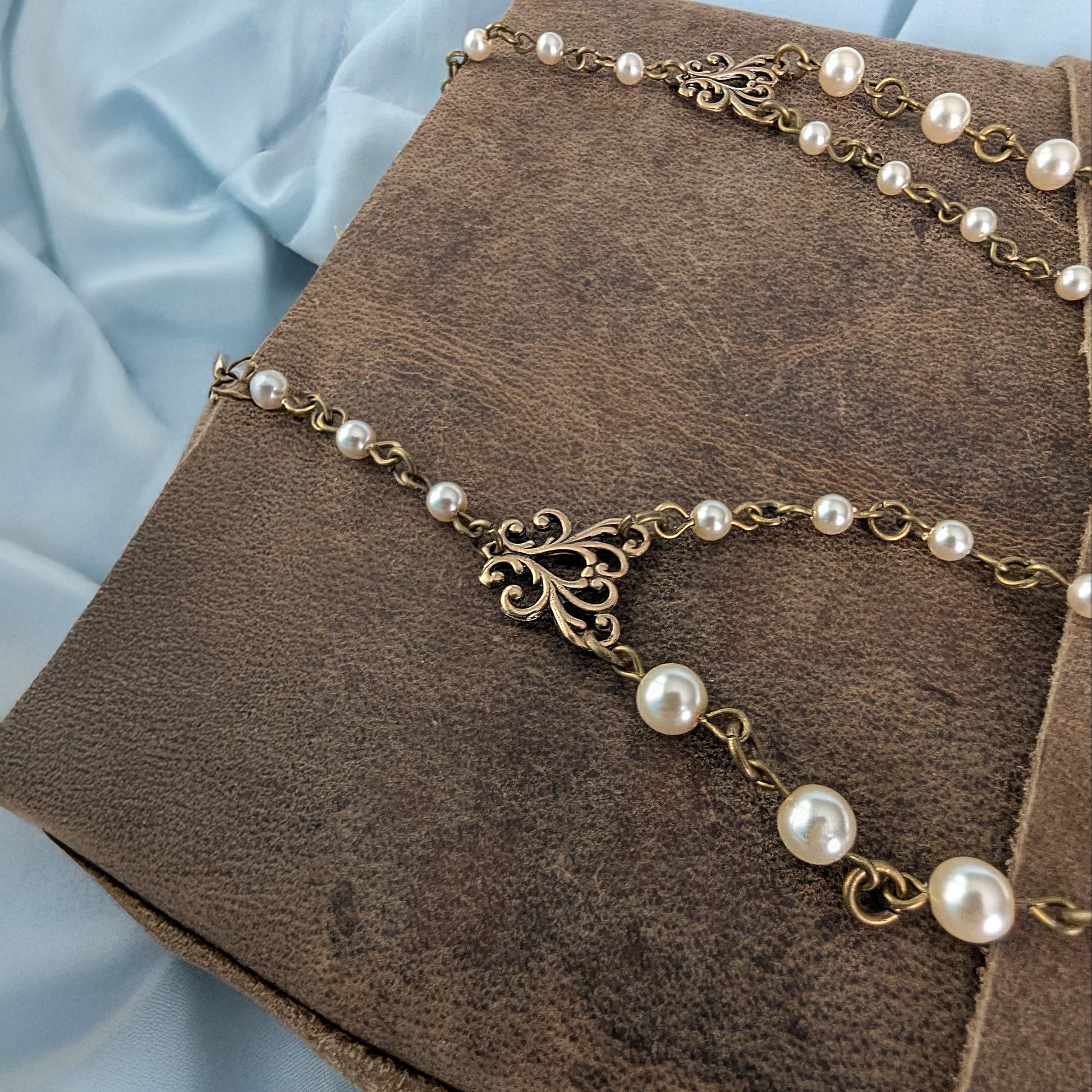 Bronze necklace with pearls on a brown textured surface