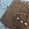 Bronze necklace with pearls on a brown textured surface