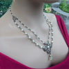 Pearl necklace with brass chain and decorative clasp on a woman wearing a red top.