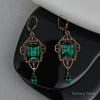 Ornate earrings with green gemstones on a reflective surface, branded 'Fantasy Trove'.