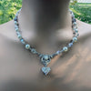Necklace with heart-shaped pendant on a woman against a blurred outdoor background