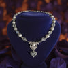 crystal and pearl Necklace with heart pendant on a blue velvet stand against a blurred purple floral background