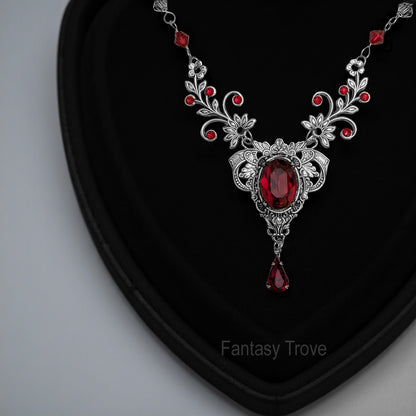 a vintage red Swarovski crystal necklace with intricate floral design displayed on a black surface.  Fairycore Vampire Jewelry Aesthetic.