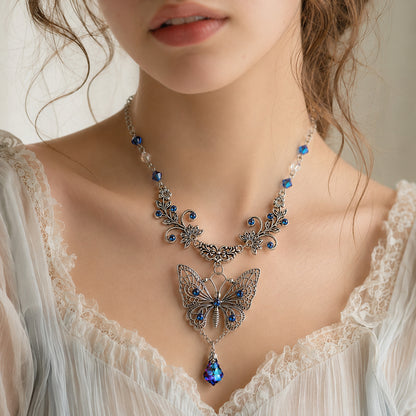 Close-up of a butterfly necklace with blue stones on a person wearing a lace top.