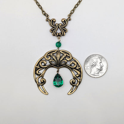 Vintage Gothic Emerald Swarovski Crystal Crescent Moon celestial pendant Necklace resting next to a quarter on a white surface