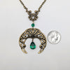 Vintage Gothic Emerald Swarovski Crystal Crescent Moon celestial pendant Necklace resting next to a quarter on a white surface