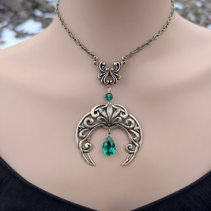 Emerald crescent moon necklace in brass with Swarovski green crystal drop displayed on a model