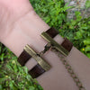 Bracelet with brown leather straps and gold chain on a wrist against a natural background