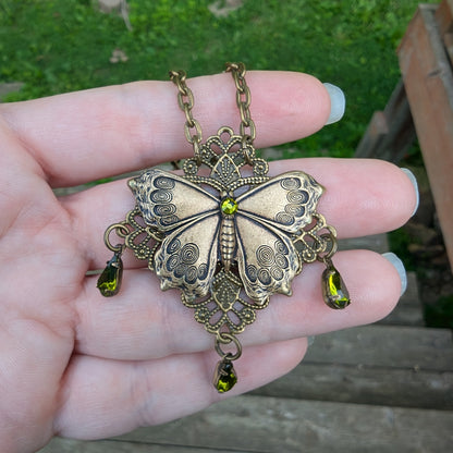 Brass Vintage Cottagecore Butterfly necklace with olivine gemstones in hand