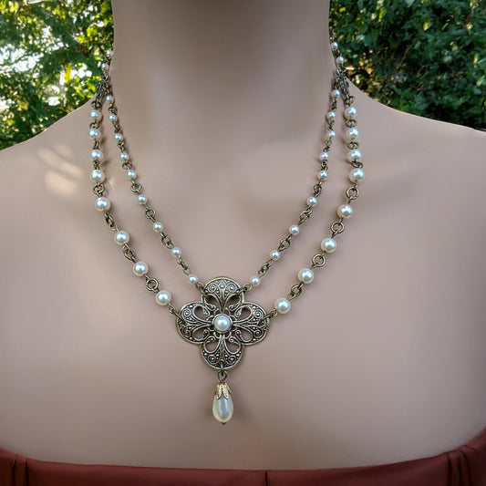 Necklace with floral pendant and pearl beads on a woman against a blurred green background