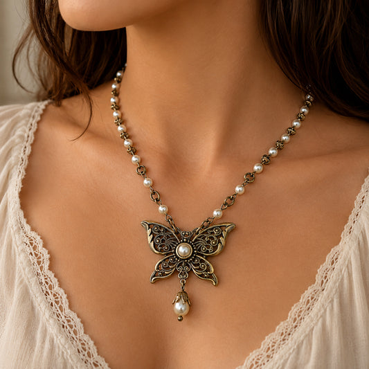 Butterfly necklace with pearl details on a person wearing a white lace top.  Vintage Brass Butterfly Necklace with Swarovski Pearls – Fairycore Victorian Jewelry