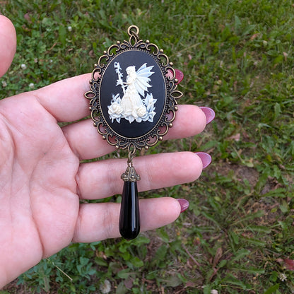 Vintage Fairy princess cameo pendant with black onyx drop bead held in hand against grassy background.  Fairycore fantasy jewelry