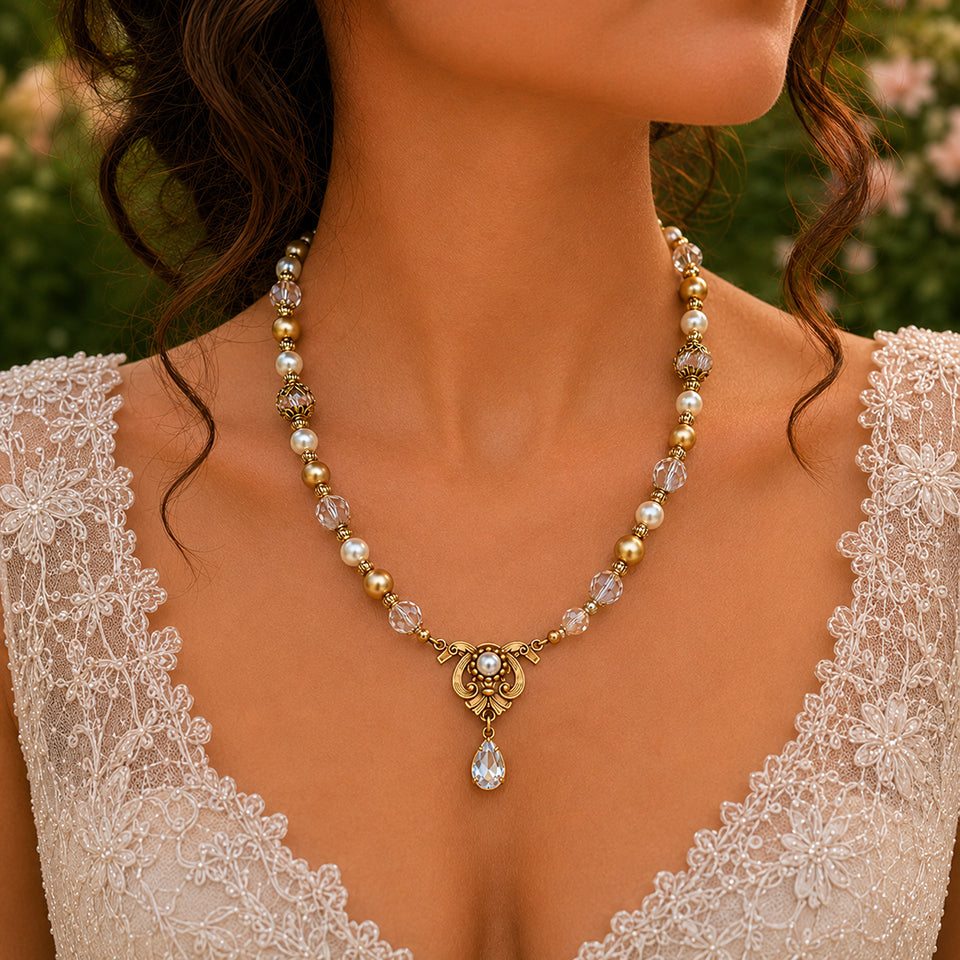 Vintage bridal Swarovski Crystal, Ivory and Gold Pearl necklace worn by a person in a lace dress with a blurred floral background.