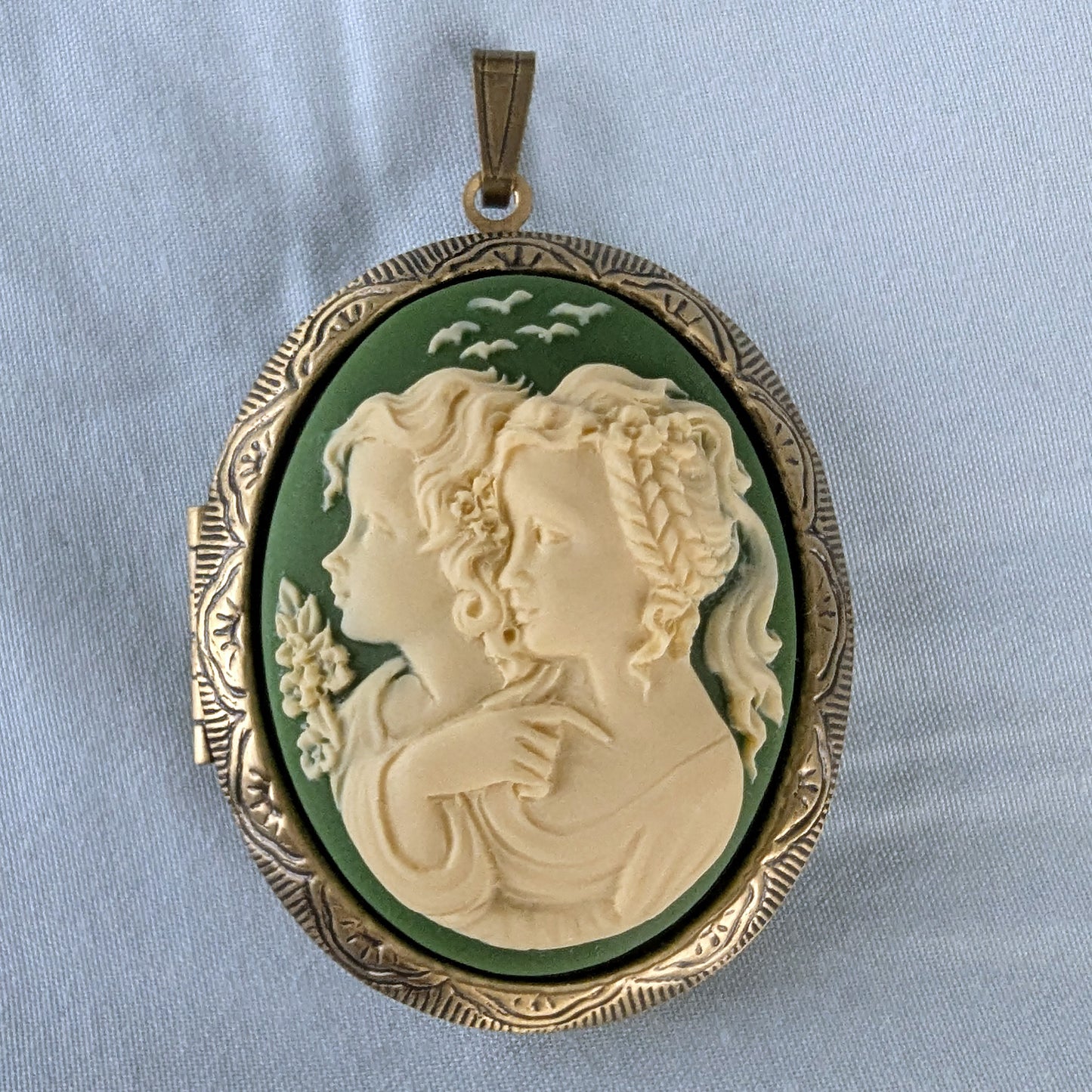 Cameo pendant with two sister profiles on a light blue background