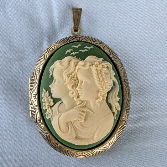 Cameo pendant with two sister profiles on a light blue background