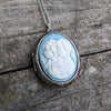 Vintage-style cameo necklace with two girls on a wooden surface