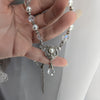 Hand holding a pearl and crystal necklace against a neutral background