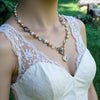 lady wearing a vintage style pearl necklace with a lace dress against a blurred green outdoor background