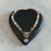 Vintage wedding bridal Necklace with heart-shaped pendant on a black heart-shaped stand against a marble background