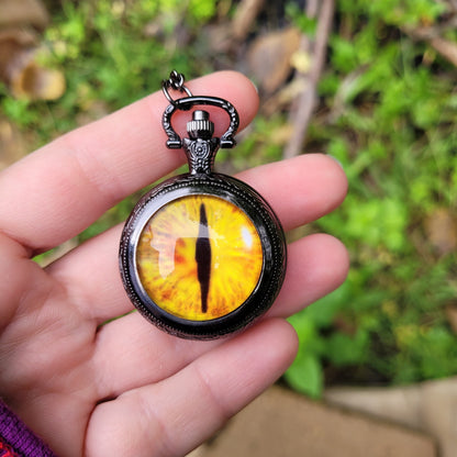 Dragon Eye Pocket Watch Necklace held in a hand outside.  Gothic Fantasy Jewelry.